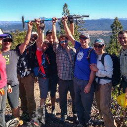 Group of trail workers on Mills Peak with their arms raised