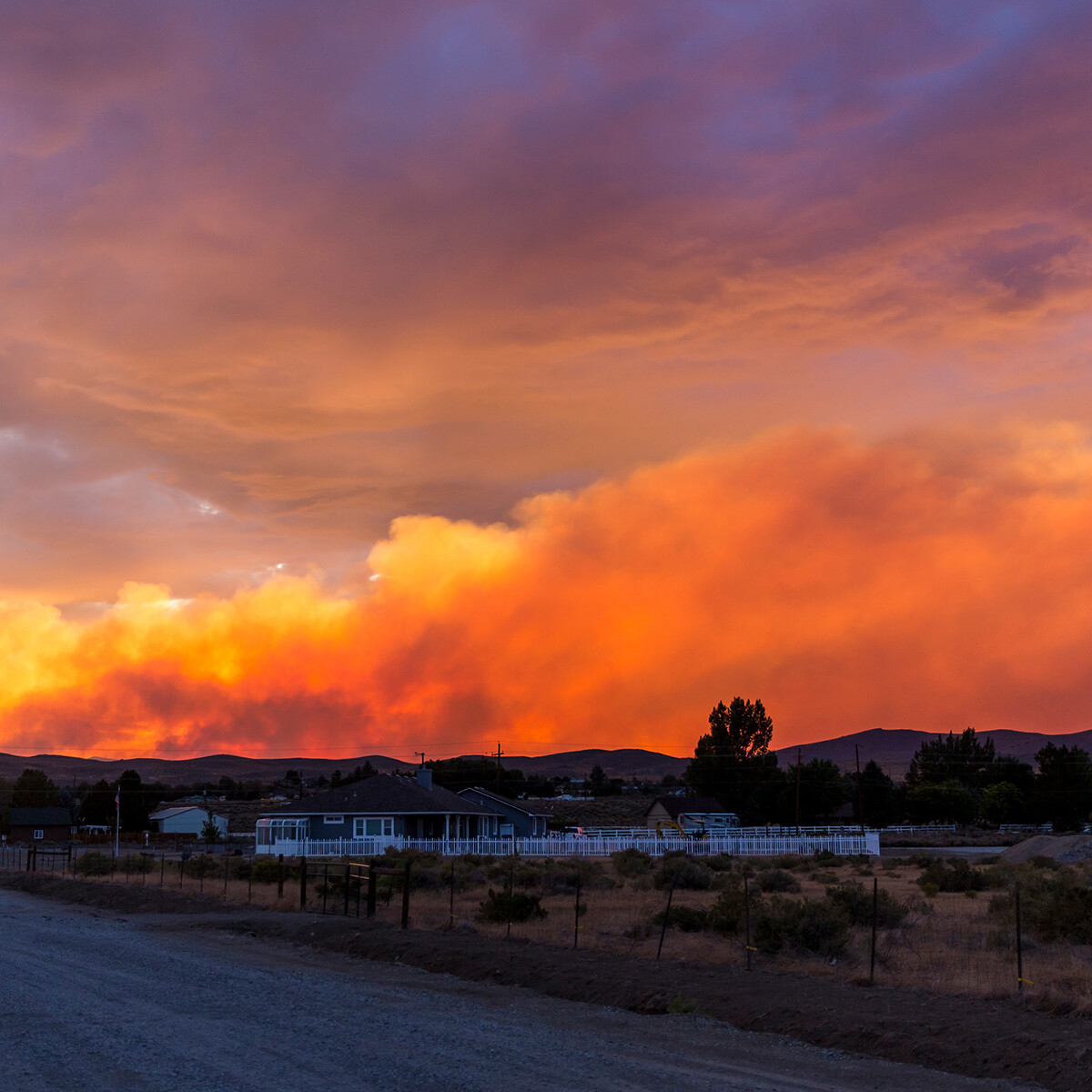 Brilliantly colored sunset in the desert over a community during a wildfire with smoke in the air road on left side