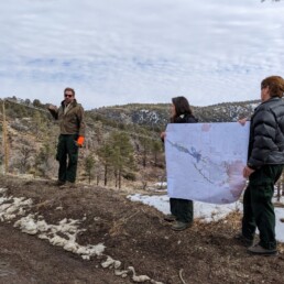 Three People Showing Map Above Forest